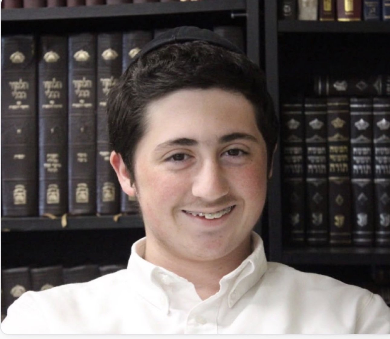 Menachem Mendel (Mendy) Vilenkin OBM, smiling in front of shelves of seforim